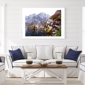 Peut inclure: Une photographie encadr&eacute;e d'un village pittoresque nich&eacute; dans une vall&eacute;e, entour&eacute; de montagnes enneig&eacute;es et d'un lac tranquille. Le village pr&eacute;sente des maisons color&eacute;es aux toits rouges et un clocher d'&eacute;glise.