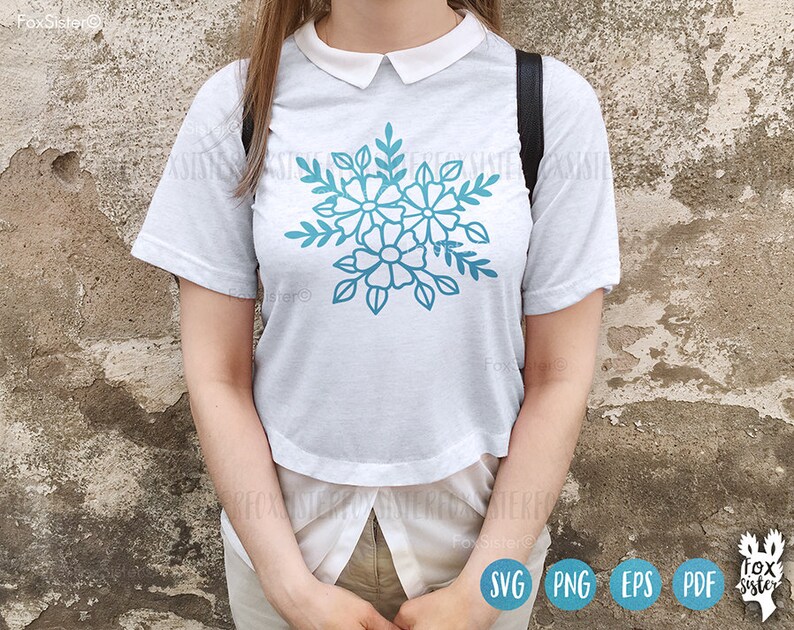 Op de afbeelding: Een wit T-shirt met een blauw bloemenontwerp. Het ontwerp toont gestileerde bloemen met meerdere bloemblaadjes en bladeren.