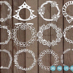 May include: A selection of white, laser-cut Christmas wreath designs, featuring candy canes, baubles, and a Christmas tree shape. The wreaths are displayed on a dark brown wooden surface.