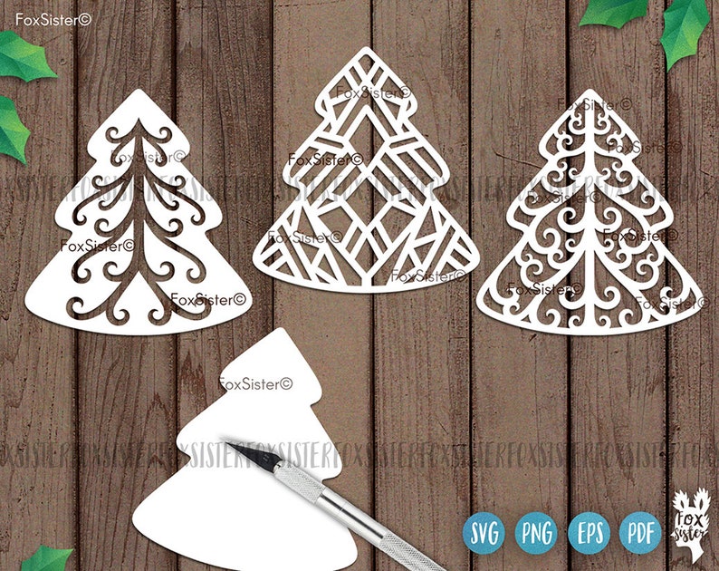 May include: Four white paper Christmas tree cutouts with intricate designs. The trees are on a wood background. The text "FoxSister" appears on the image.