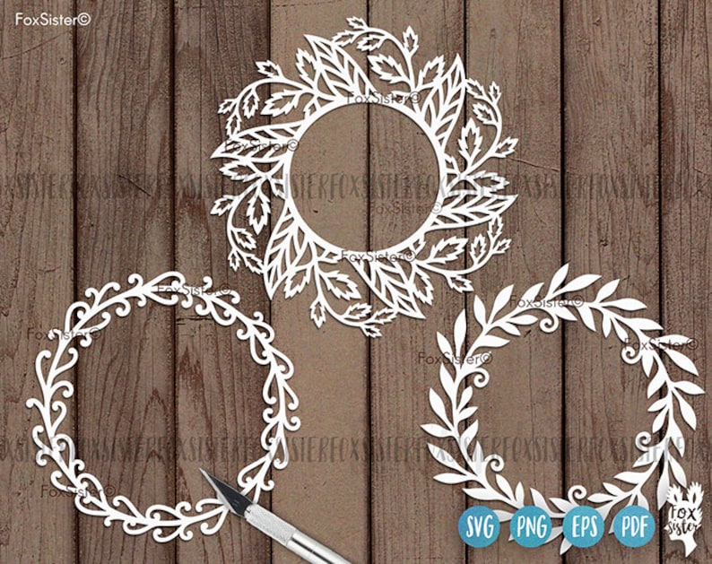 May include: Three white, decorative, paper cut-out wreaths with intricate floral designs. The wreaths are on a woodgrain background. The text "SVG PNG EPS PDF" is at the bottom of the image.