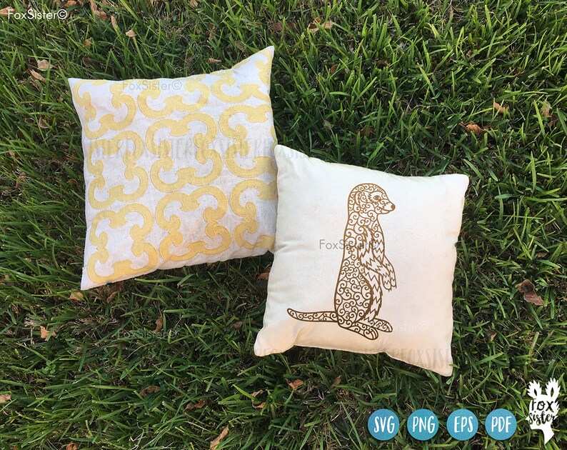 May include: Two white pillow covers with brown embroidery. One pillow has a geometric pattern and the other has a detailed outline of a meerkat.