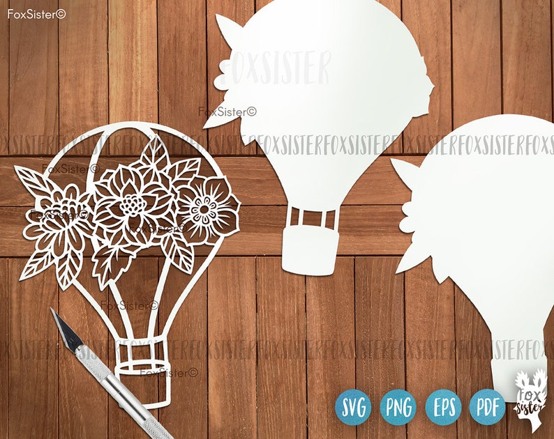 May include: White silhouette of a hot air balloon with floral designs, on a wood background. The balloon has a basket and a rope attached to it. The image also includes the text "FoxSister" and the file formats "SVG, PNG, EPS, PDF".