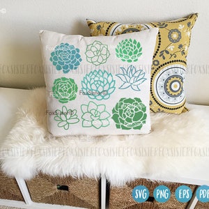 May include: A white pillow with a green and blue succulent design. The pillow has the text "FoxSister" on it. The pillow is sitting on a white faux fur throw.