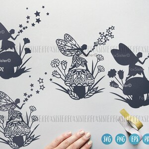 May include: Three black silhouette designs of fairies blowing stars. Each fairy is sitting on a mushroom with intricate details. The designs are perfect for crafting and decorating.