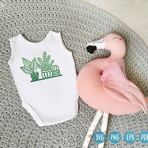 May include: White bodysuit with a green graphic of potted plants. The bodysuit is on a gray knitted surface with a pink flamingo pillow.