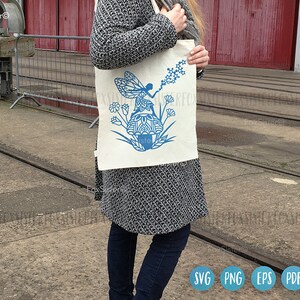 May include: A white tote bag with a blue fairy design. The fairy is sitting on a mushroom and holding a wand with stars. The bag has the text "Fox Sister" on it.