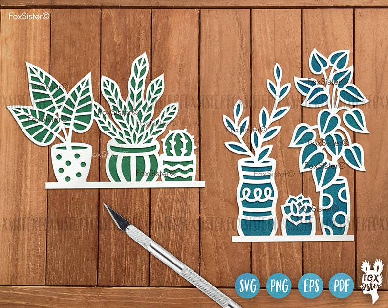 May include: SVG cut file design of three potted plants. The plants are a cactus, a leafy plant, and a fern. The pots are white with a teal design. The design is on a wood background.