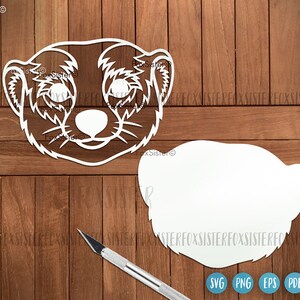 May include: A white cutout of a meerkat face with a blank white cutout of a meerkat body. The cutouts are on a wood background.