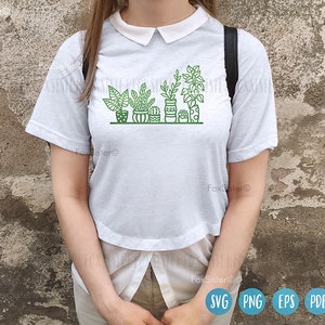 May include: White t-shirt with a graphic of potted plants in green and black outlines. The plants are in different shapes and sizes, and the pots are all different colors.