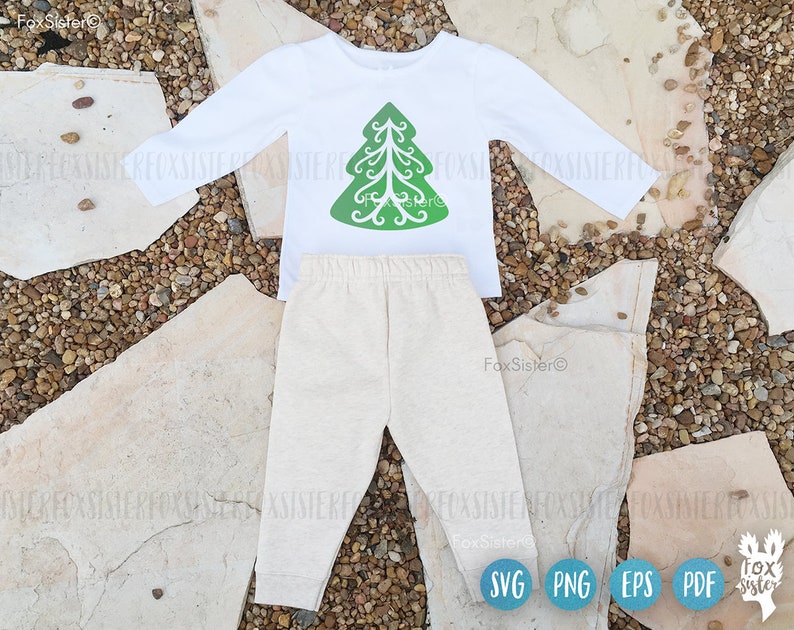 May include: A white long-sleeved shirt with a green Christmas tree design on the front. The shirt is paired with beige pants. The image includes the text "FoxSister" and the file formats "SVG", "PNG", "EPS", and "PDF".