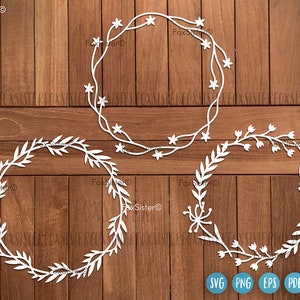 May include: Three white paper cut-out wreaths with floral designs. The wreaths are on a woodgrain background. The text "SVG PNG EPS PDF" is at the bottom of the image.