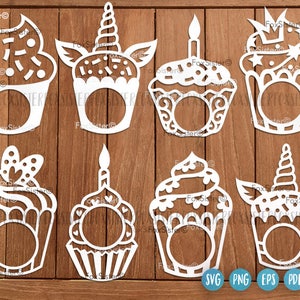 May include: A collection of eight white cupcake-shaped cutouts, each with a unique design. Some feature sprinkles, a candle, a unicorn horn, or a crown. The cutouts are arranged on a wooden background, with SVG, PNG, EPS, and PDF file type icons.