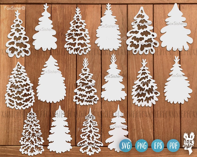 May include: A set of 12 white, cut-out Christmas tree shapes on a wood background. The trees are in various sizes and styles. The text "FoxSister" appears on the image.