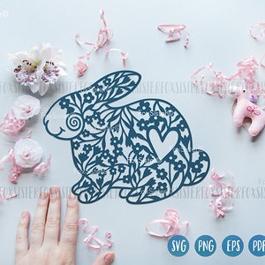May include: A blue floral bunny rabbit silhouette with a heart in the center. The bunny is surrounded by pink and white confetti.