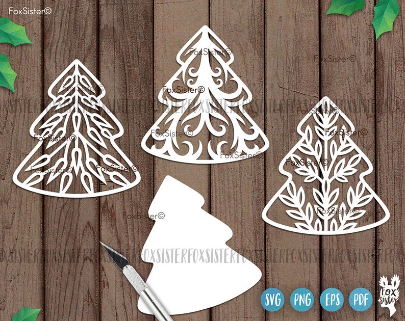 May include: Four white paper cut-out Christmas tree designs. The trees are different styles, with one being a simple outline, one with a leafy design, one with a swirling design, and one with a more intricate design. The trees are on a wood background.