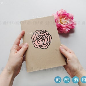 May include: A brown card with a pink and black outline of a rose on it. The card is being held by a hand.