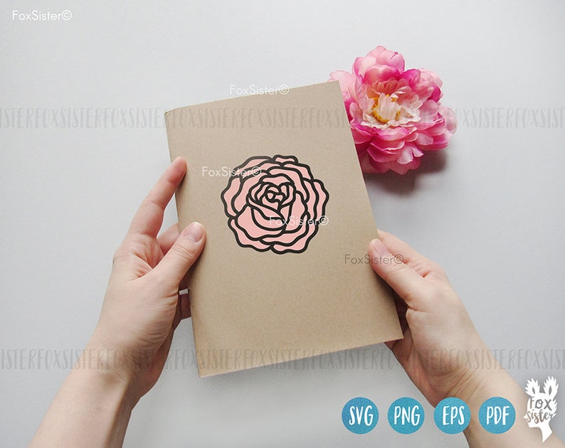 May include: A brown card with a pink and black outline of a rose on it. The card is being held by a hand.