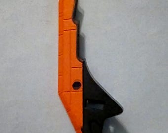May include: Orange and black plastic toy weapon with a sharp point and a textured surface.