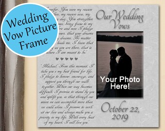 May include: A gray and white dual table-top and wall frame with a wedding vow picture frame. The frame has a gray background with a white border and a white mat. The frame has a photo insert with the text "Our Wedding Vows" and "Your Photo Here!" The frame also has the text "October 22, 2019".