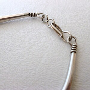 May include: Silver bracelet with a simple, curved design and a lobster claw clasp.