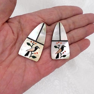 May include: A pair of teardrop-shaped earrings featuring inlaid mother-of-pearl segments separated by thin black lines. Each earring displays a small bird perched on a branch with green leaves and orange berries, crafted from various stone inlays.