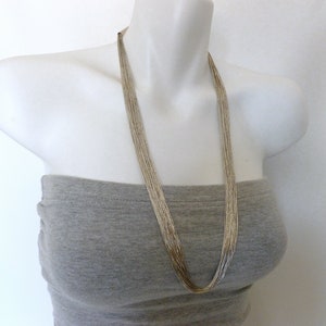 May include: A silver chain necklace with multiple strands, worn on a mannequin with a gray top.