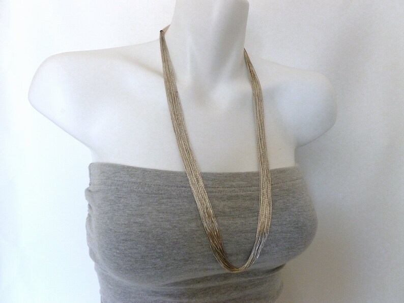 May include: A silver chain necklace with multiple strands, worn on a mannequin with a gray top.