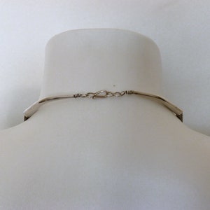May include: The back of a silver necklace with a clasp closure.