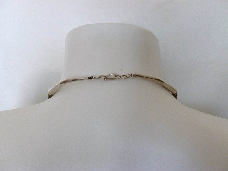 May include: The back of a silver necklace with a clasp closure.