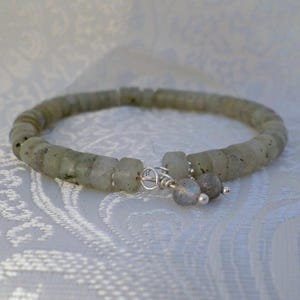 Puede incluir: Pulsera de cuentas cilíndricas verde claro. Tiene un cierre plateado y dos pequeños abalorios redondos plateados. Las cuentas son ligeramente translúcidas. Circunferencia de unos 18 cm.