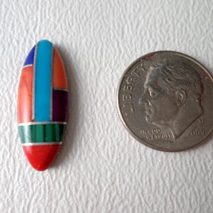May include: A small, oval-shaped, multi-colored stone inlay pendant. The inlay features turquoise, red, green, purple, and blue stones.