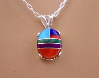 May include: A silver necklace with a multi-colored oval pendant. The pendant is made of turquoise, red coral, green malachite, purple amethyst, and blue lapis lazuli.