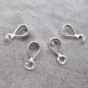 May include: Four silver-toned metal jewelry bails, each featuring a teardrop-shaped loop at the top for suspension and a small circular ring at the bottom for attaching pendants or charms to necklaces or bracelets.