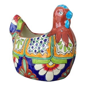May include: A ceramic hen-shaped planter with a vibrant, hand-painted design. The planter features a red comb, blue beak, and a body adorned with colourful floral and geometric patterns in shades of blue, orange, green, and white. The planter is a decorative item.