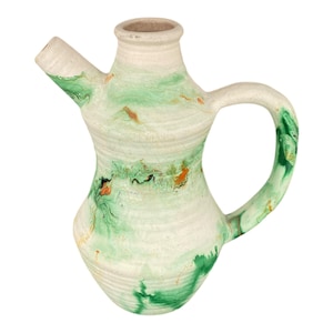 May include: A handmade ceramic pitcher with a spout and handle. The pitcher features a white base with green and orange marbled patterns. The handle and spout are also decorated with green marbling. The pitcher has a unique, organic shape.