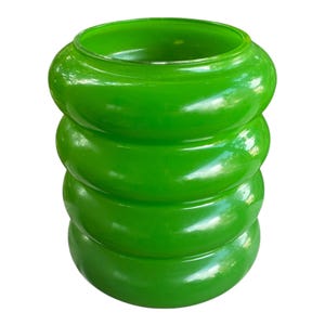 May include: A bright green glass vase with a distinctive stacked ring design. The vase features a wide opening and a glossy finish. The stacked rings create a textured, appealing look. This decorative item is suitable for various home decor styles.