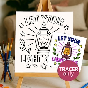 Puede incluir: Un caballete de madera muestra una página para colorear con el texto "LET YOUR LIGHT SHINE" y una ilustración de una linterna. Una versión más pequeña y coloreada del diseño está al lado. Hay botes de pintura y pinceles cerca.