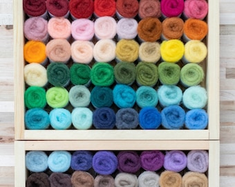 May include: A wooden box filled with rows of colorful wool roving. The roving is arranged in a rainbow pattern, with shades of red, orange, yellow, green, blue, purple, and brown.