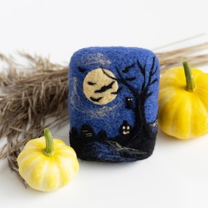 May include: A blue felt soap featuring a Halloween scene with a full moon, bats, a tree, and a spooky house. Two small yellow gourds are in the foreground.