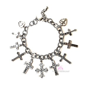 Könnte beinhalten: Ein silbernes Charm-Armband mit mehreren Kreuz-Anhängern. Das Armband hat ein Kettenglied-Design und ist mit verschiedenen Kreuz-Anhängern verziert, darunter ein herzförmiges Kreuz, ein Kreuz mit Flügeln und ein Kreuz mit einem floralen Design.