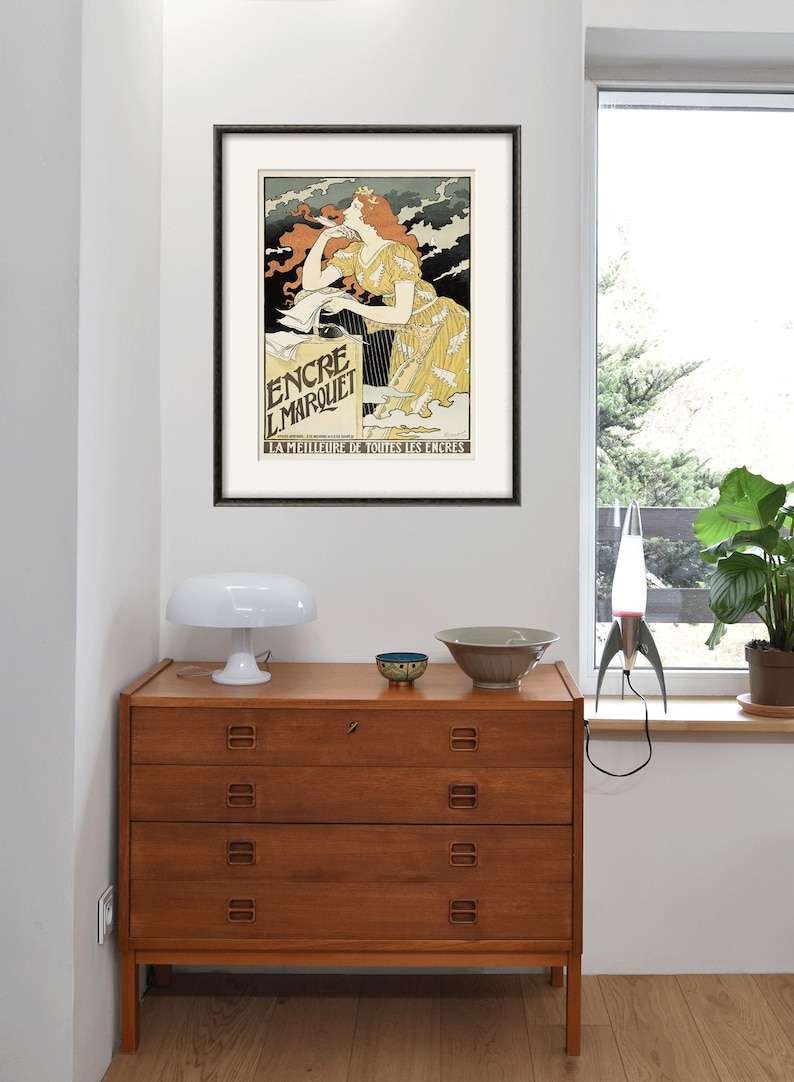 May include: A vintage poster advertising "Encre L'Marquet" ink. The poster features a woman in a yellow dress writing with a pen. The text "La Meilleure de Toutes les Encres" is at the bottom of the poster.