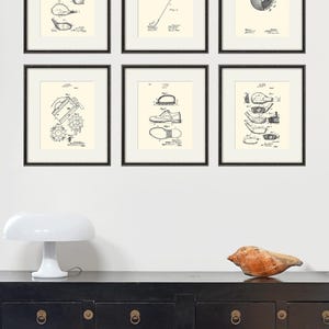 Puede incluir: Seis impresiones enmarcadas en negro de dibujos de patentes vintage relacionados con el golf. Las impresiones se muestran en una pared blanca sobre una c&oacute;moda negra con herrajes dorados.