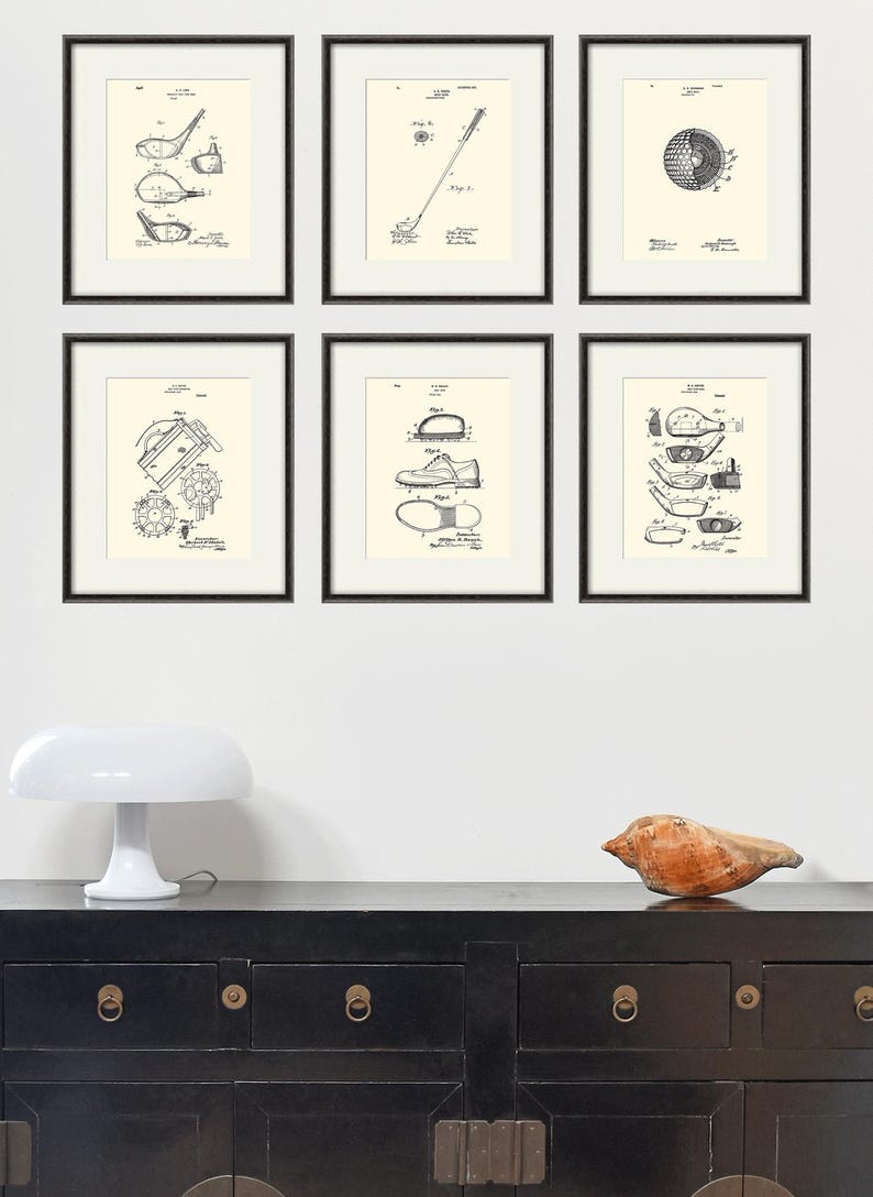 Puede incluir: Seis impresiones enmarcadas en negro de dibujos de patentes vintage relacionados con el golf. Las impresiones se muestran en una pared blanca sobre una c&oacute;moda negra con herrajes dorados.