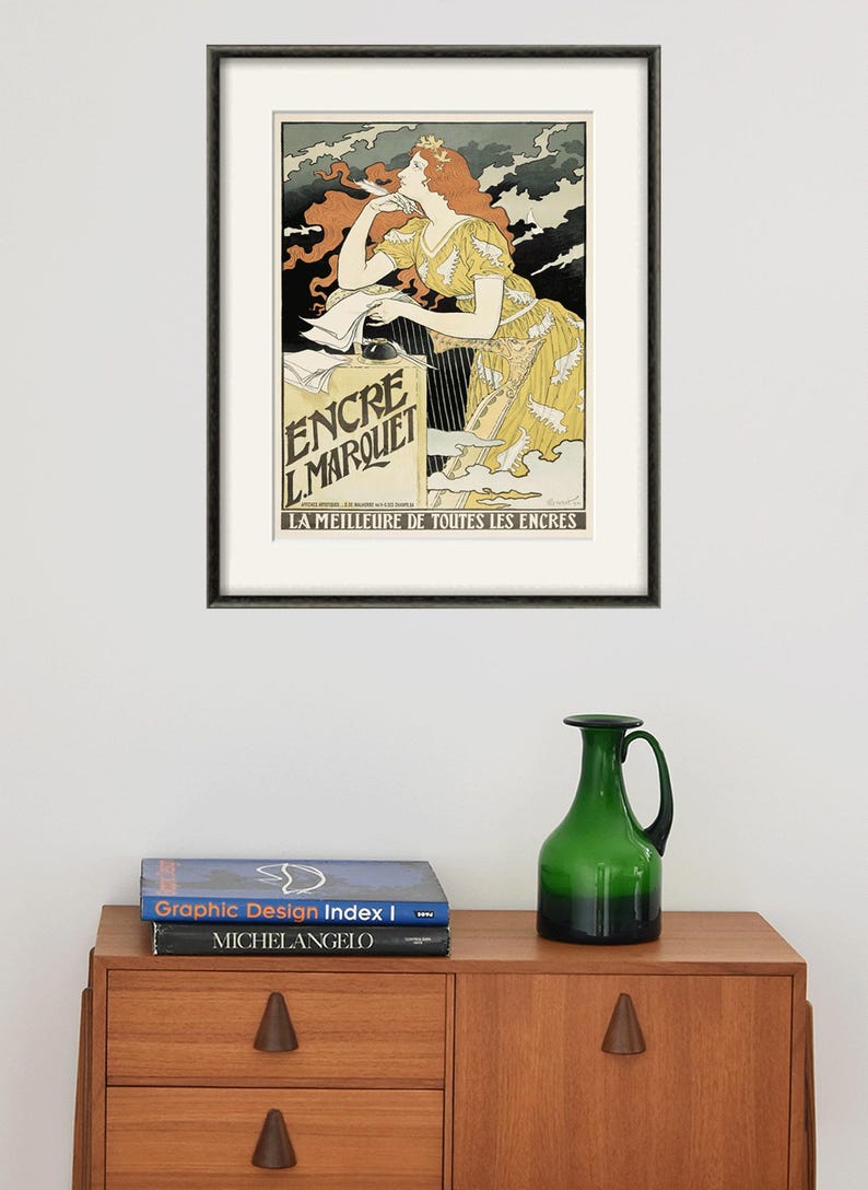 May include: A vintage poster advertising "Encre L'Marquet" ink. The poster features a woman with red hair writing at a desk with a quill pen. The text "LA MEILLEURE DE TOUTES LES ENCRES" is at the bottom of the poster.