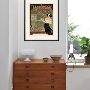 Peut inclure: Une affiche vintage pour le Teatro Regio de Turin, en Italie. L'affiche repr&eacute;sente une femme jouant du harpe avec un blason et les mots "Teatro Regio Torino" en arri&egrave;re-plan.