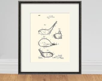 Puede incluir: Impresión enmarcada de patente de palo de golf vintage. La impresión presenta dibujos técnicos detallados de un palo de golf, con múltiples vistas y componentes etiquetados. La obra de arte es en blanco y negro, sobre un fondo crema, y enmarcada en un marco negro.