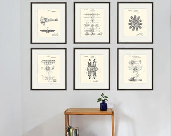 Könnte beinhalten: Neun gerahmte Schwarzweiß-Zeichnungen von Vintage-Flugzeugpatenten an einer weißen Wand. Die Zeichnungen zeigen verschiedene Flugzeugtypen und Motoren. Die Zeichnungen sind alle im gleichen Stil gehalten und alle in schwarzen Rahmen gerahmt.
