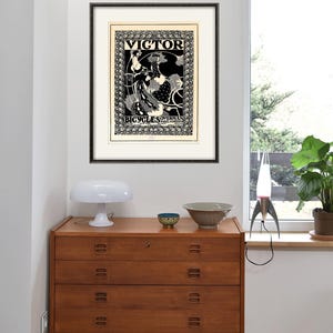 Pu&ograve; includere: Un poster vintage in bianco e nero che pubblicizza le biciclette Victor, con una donna che guida una bicicletta con un design floreale.