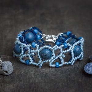 Op de afbeelding: Een blauwe en witte kralen armband met een geometrisch ontwerp. De armband heeft donkerblauwe kralen en lichtblauwe kralen.